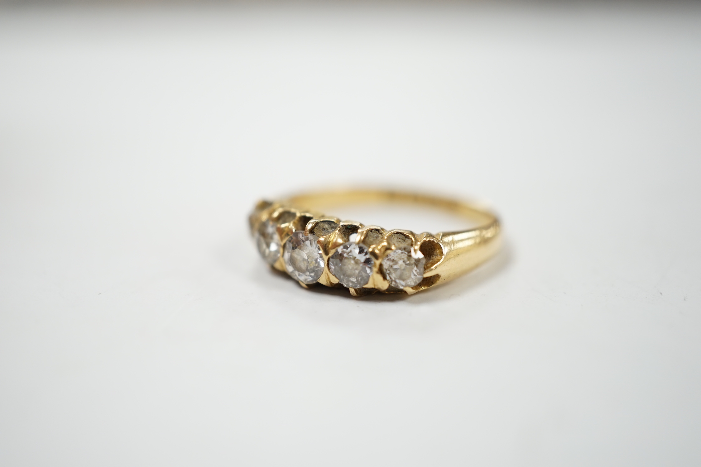 A late Victorian 18ct gold and graduated five stone diamond set half hoop ring, size L/M, gross weight 3.6 grams.